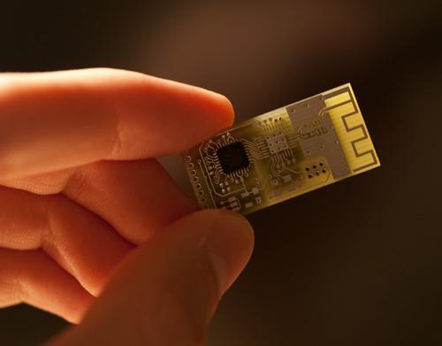 fingers holding the circuit board with the microcontroller soldered
        into place